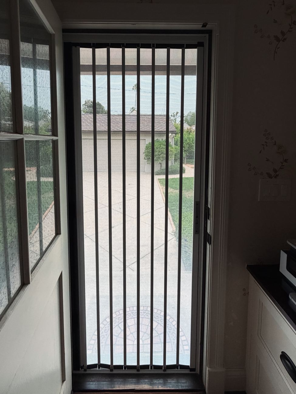 View from inside through a folding screen on a single door to the driveway