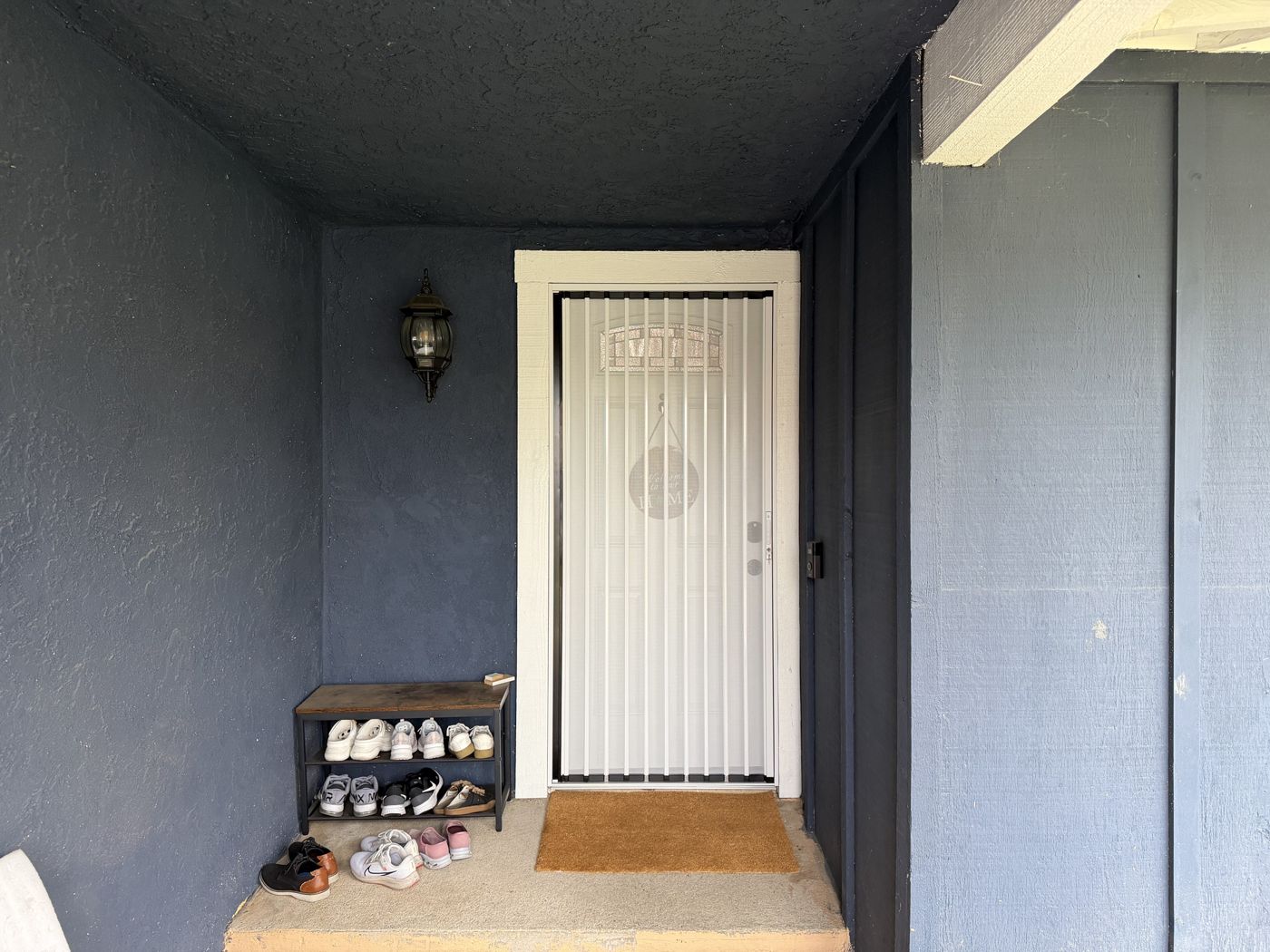 White folding screen on a front door in a blue-painted porch